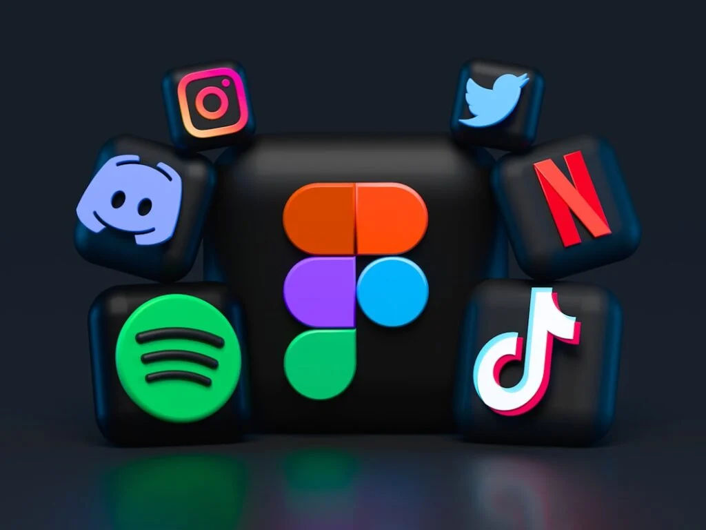 In image-2, 3D icons of apps like Spotify, Instagram, Discord, Twitter, TikTok, Netflix, and Figma encircle a large central icon. The dark background enhances the icons' vibrant colors.
