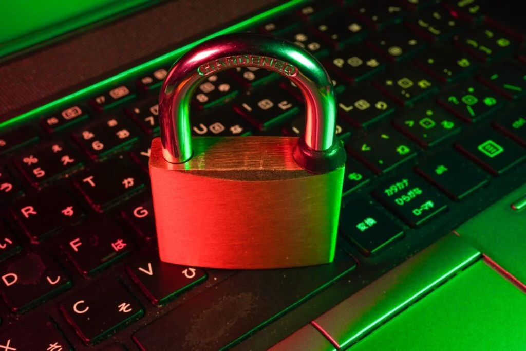 The image shows a padlock on a laptop keyboard, symbolizing cybersecurity. Red and green lighting accentuates Japanese characters on the keys in product image-6.