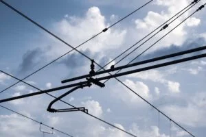 In image-2, overhead electric power lines and cables cross beneath a bright sky with scattered clouds.