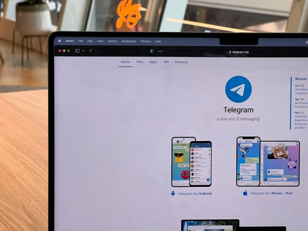 Image-7 shows a laptop on a wooden table in a bright, modern indoor setting, displaying the Telegram homepage with the logo, description, and app download options for Android and iPhone.
