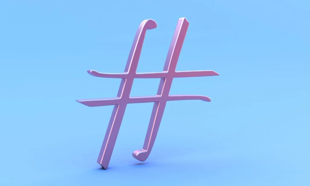 The image features a large, glossy pink hashtag symbol standing upright against a smooth, light blue background.