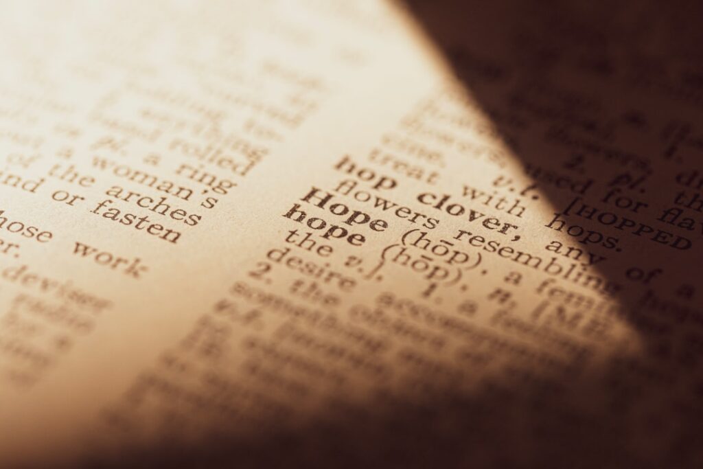 Image-4 features a close-up of a dictionary page focused on the word "hope" and its definition, illuminated by a warm beam of light, with the surrounding text artistically blurred.