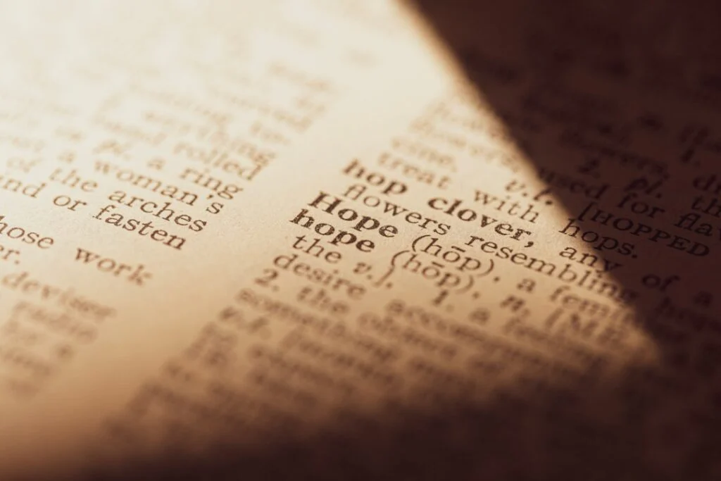 Image-4 features a close-up of a dictionary page focused on the word "hope" and its definition, illuminated by a warm beam of light, with the surrounding text artistically blurred.