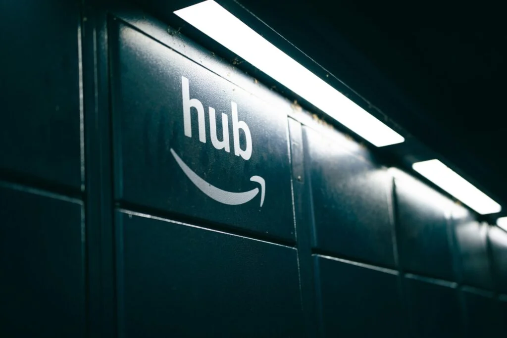 A close-up of 060920261788657418.jpeg featuring a dark wall with the word “hub” and the Amazon smile logo illuminated by overhead lights.