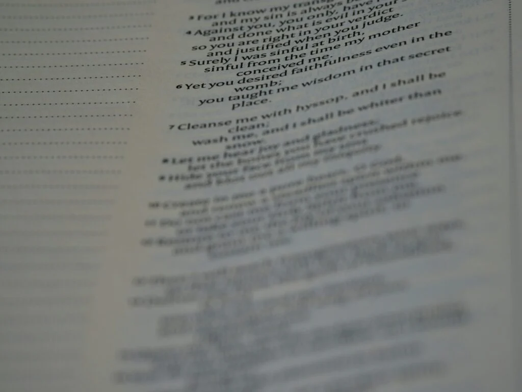 A close-up photo of 140920261789348634.jpeg features a page from the Bible, with the text slightly out of focus—only a few lines are somewhat readable, while the rest of the words appear blurred.