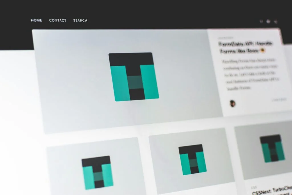 A computer screen displays the 180920261789694206.jpeg website, featuring a teal and black geometric logo in the center, navigation links at the top, and a sidebar with text and article previews.
